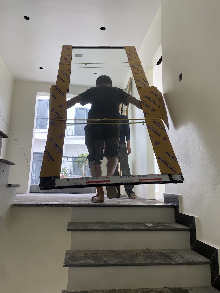 Thợ đang lắp đặt cửa kính cường lực khung nhôm tại cầu thang trong nhà